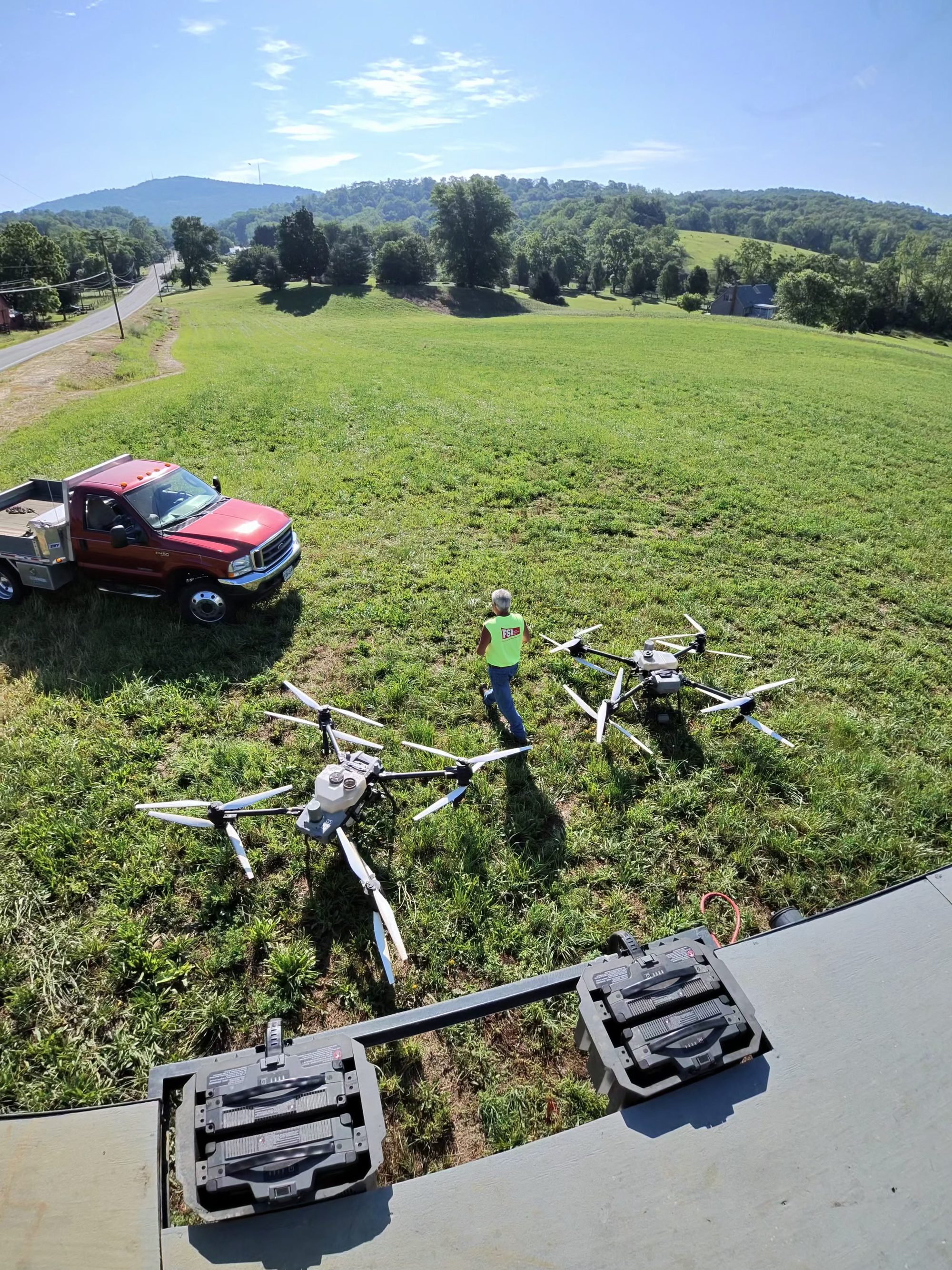 Two spray drones and the service truck staged at the field edge