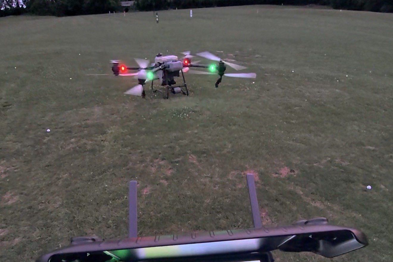 Spray drone over a golf driving range at dusk